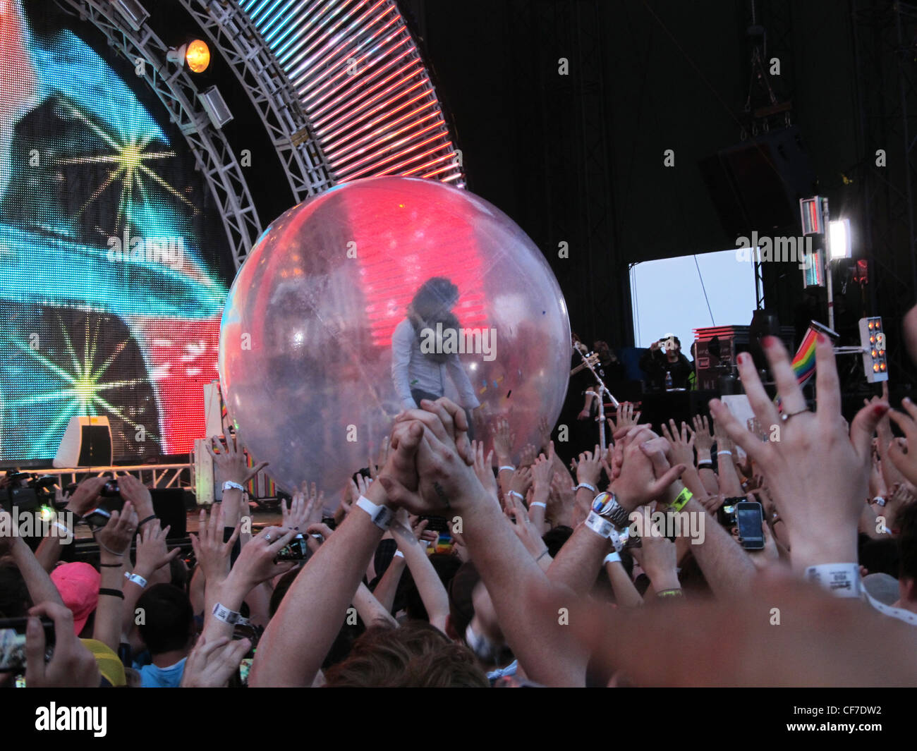 Il cantante per Flaming Lips sorge all'interno di una sfera di plastica e naviga la folla di tifosi a un festival di musica. Foto Stock