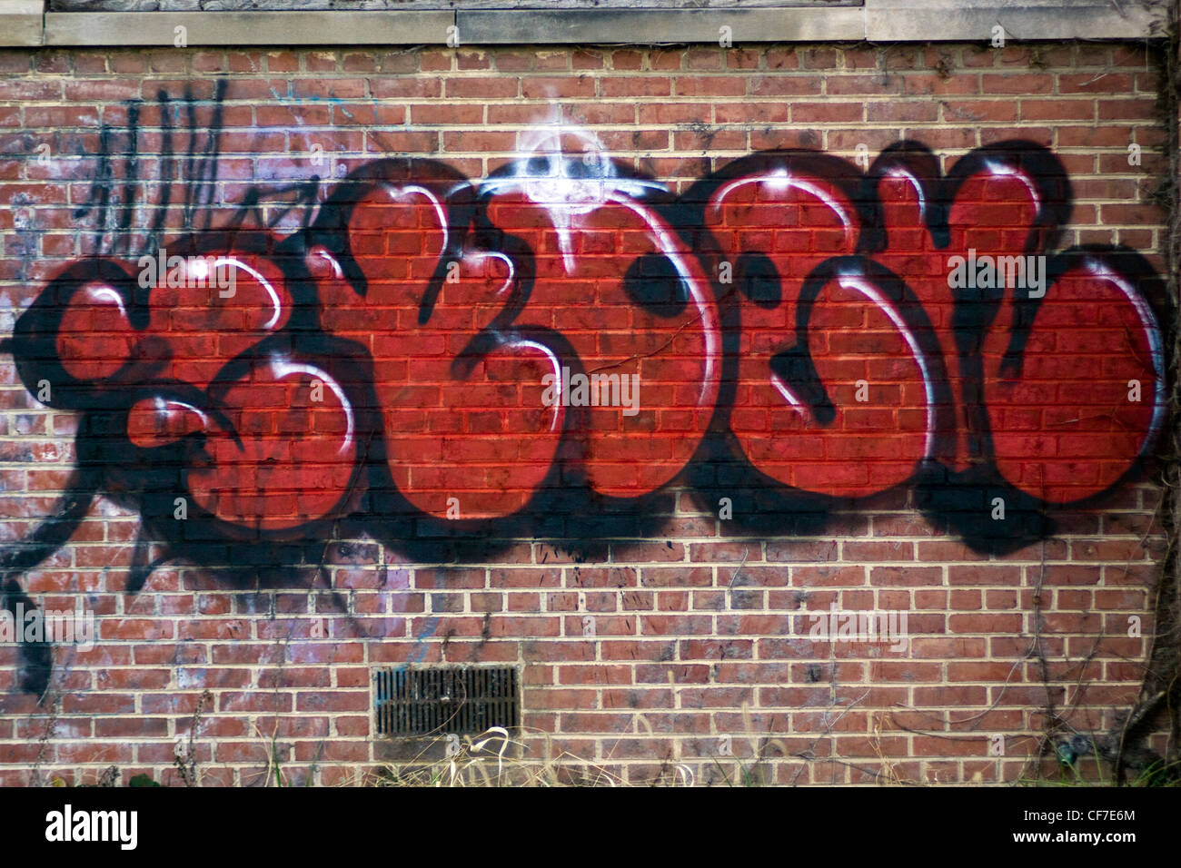 Graffiti verniciato a spruzzo su un mattone parete magazzino in Shirlington senza personalità area urbana Arlington County Foto Stock