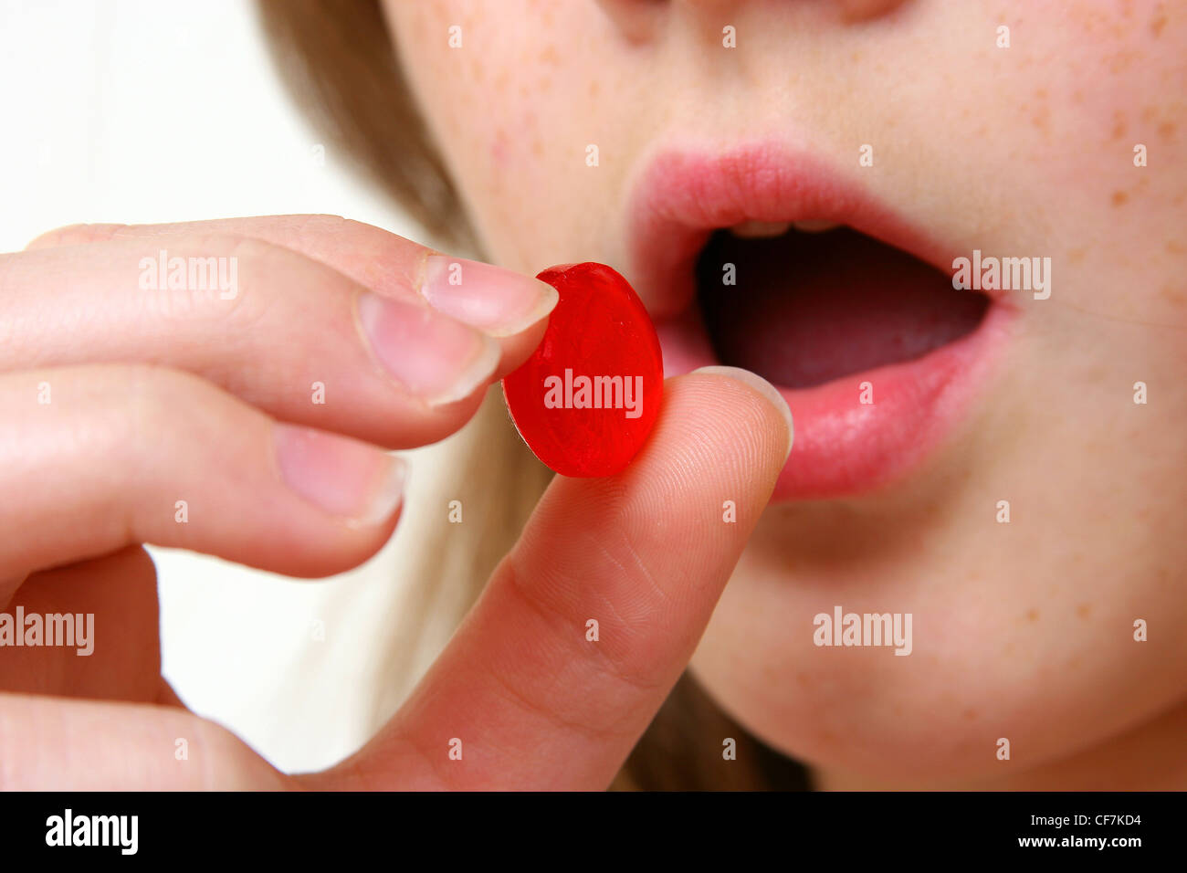 Una giovane donna che sta per mettere un rosso losanga di gola nella sua bocca Foto Stock
