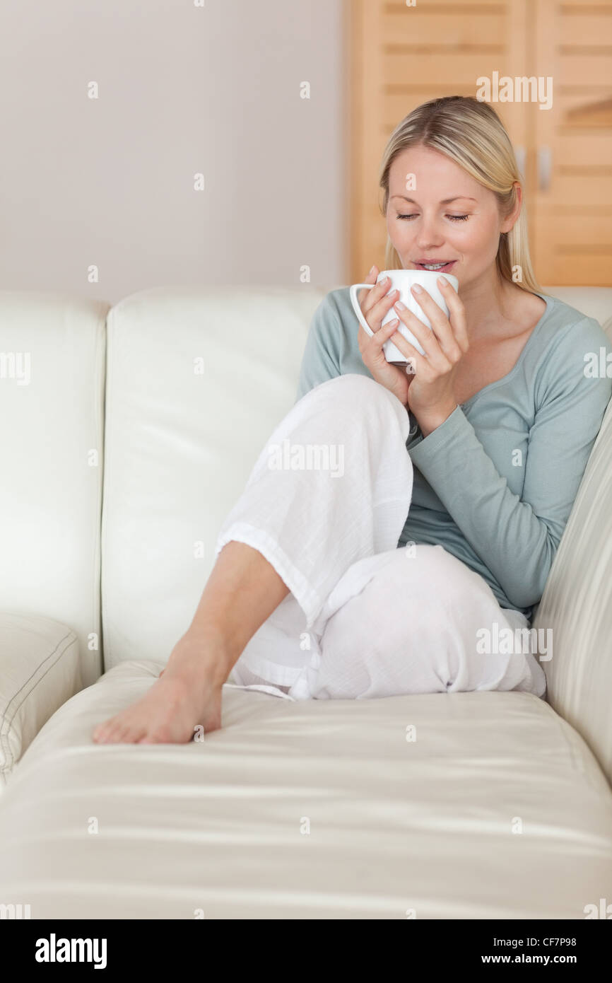 Donna sul divano di prendere un sorso di caffè Foto Stock