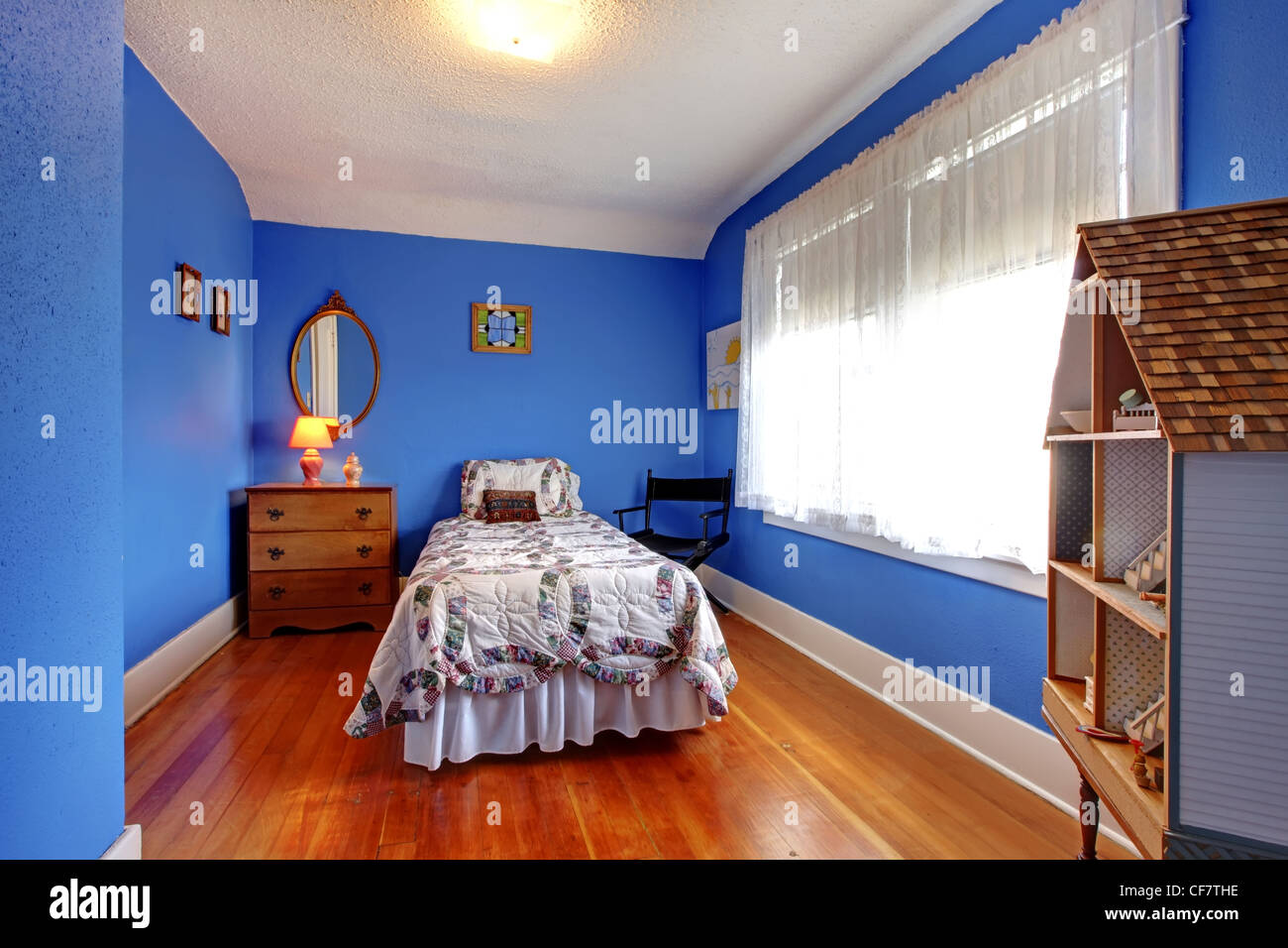 Blu luminosa camera da letto per bambini in un vecchio stile Inglese con cherry pavimento in legno duro e casa di bambola. Foto Stock