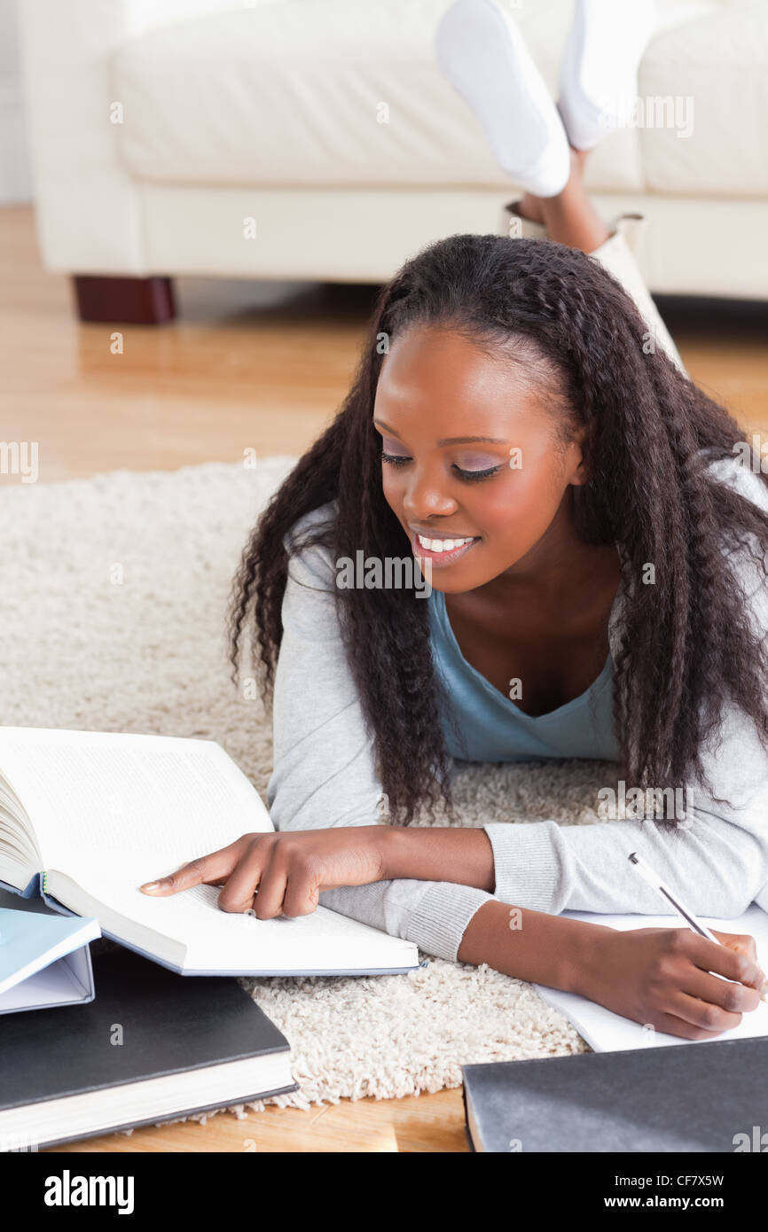Donna sdraiata sul pavimento lavorando su una recensione del libro Foto Stock