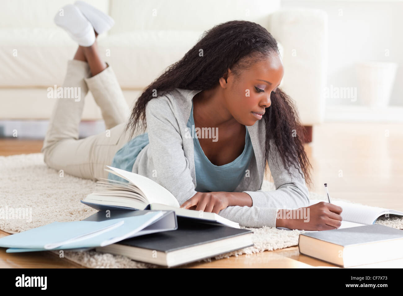 Donna sdraiata su un tappeto lavorando su recensione del libro Foto Stock
