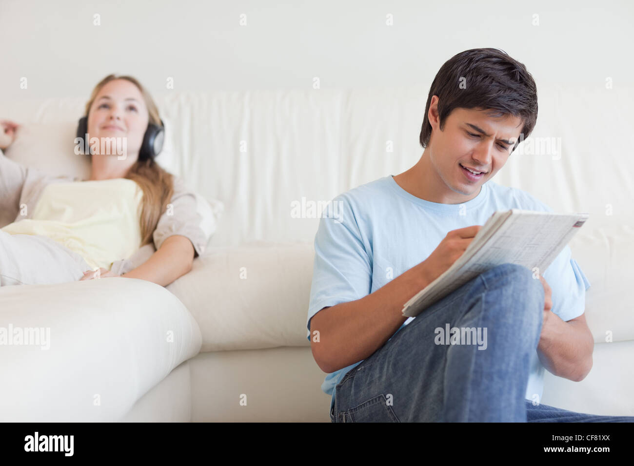Uomo che fa le parole crociate mentre sua moglie è l'ascolto di musica Foto Stock