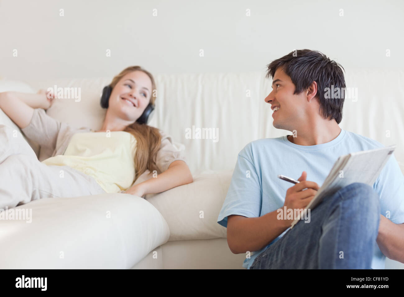 Uomo che fa le parole crociate mentre la sua ragazza è l'ascolto di musica Foto Stock