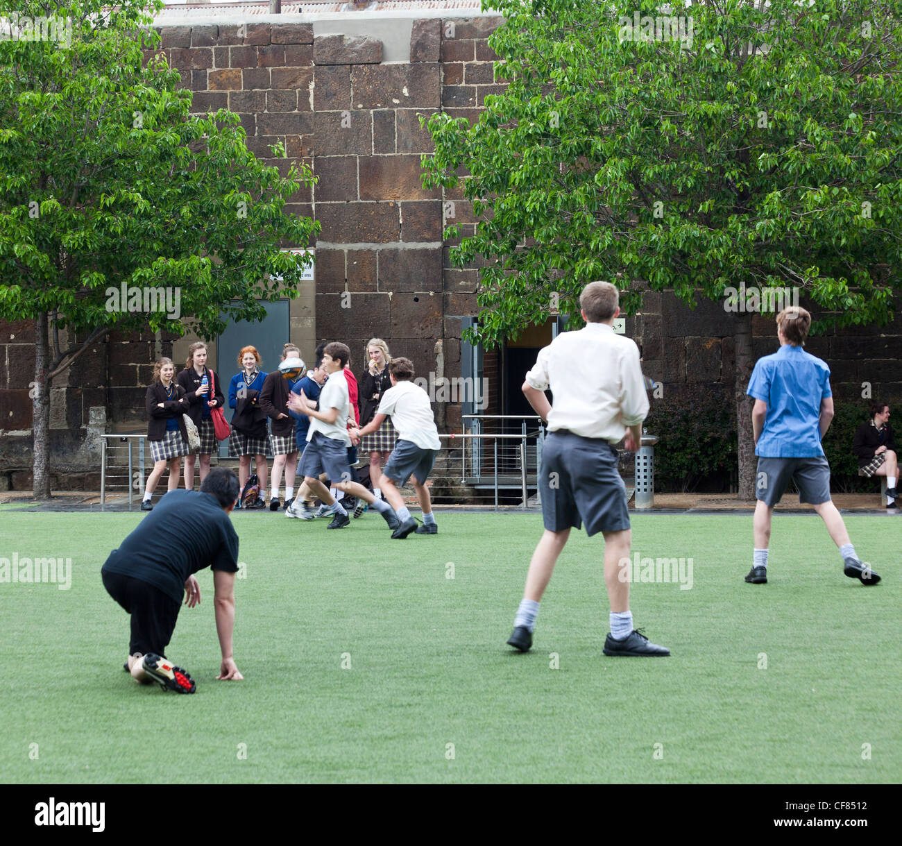 Scolari riproduzione touch rugby guardato da ammirando studentesse, Melbourne, Australia Foto Stock