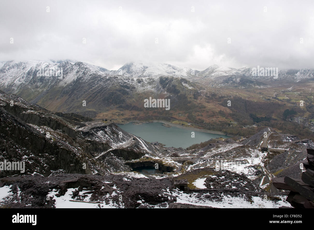 Edifici in disuso e rifiuti di ardesia guardando oltre Llyn Peris in cava di Dinorwig a Llanberis Galles del Nord Foto Stock