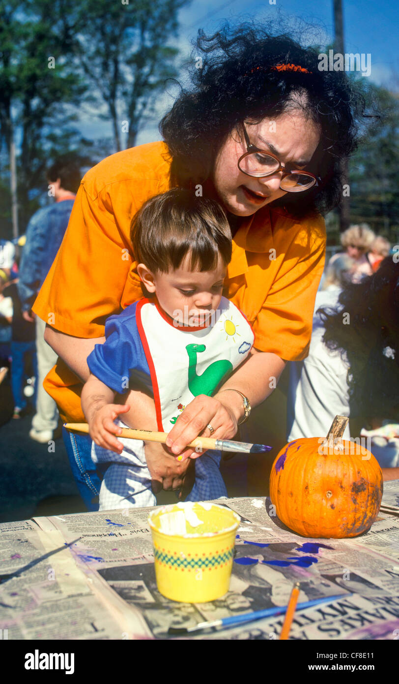 Una madre e suo figlio vernice una zucca di Halloween. Foto Stock