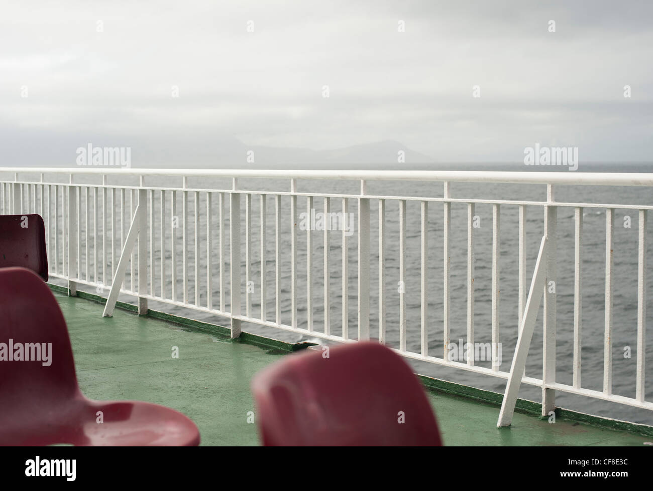 Vista da un traghetto di mare coperta con plastica sedie rosse in primo piano e orizzonte in distanza in Scozia. Foto Stock