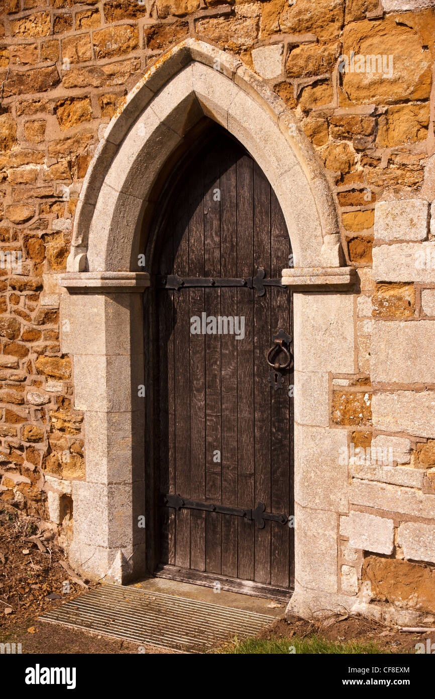 Antica pietra appuntita arco gotico porta con la porta di legno, St. Swithun's Chiesa, grande Dalby, Leicestershire, England, Regno Unito Foto Stock