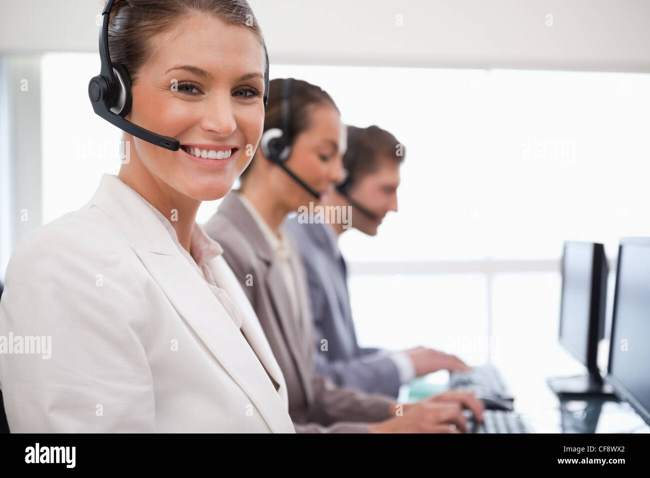 Sorridente call center agent colleghi dietro di lei Foto Stock
