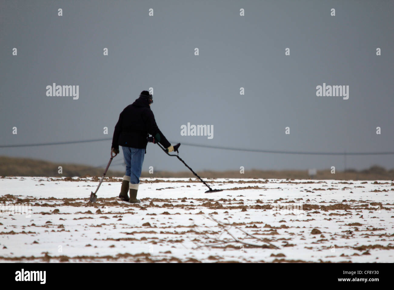 Un rivelatore di metalli la ricerca di un tesoro sepolto in una coperta di neve campo Foto Stock