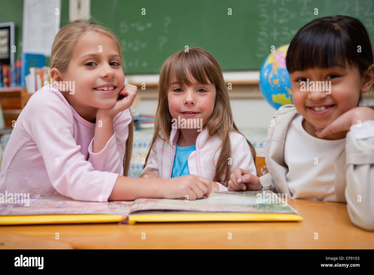 Felice scolare la lettura di una fiaba per il loro compagno di classe Foto Stock