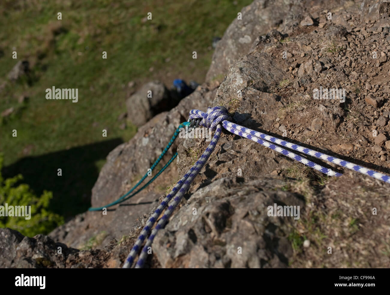 Una fune di arrampicata sentieri verso il basso roccia dolerite da una altezza al Auchinstarry cava, Scozia. Foto Stock