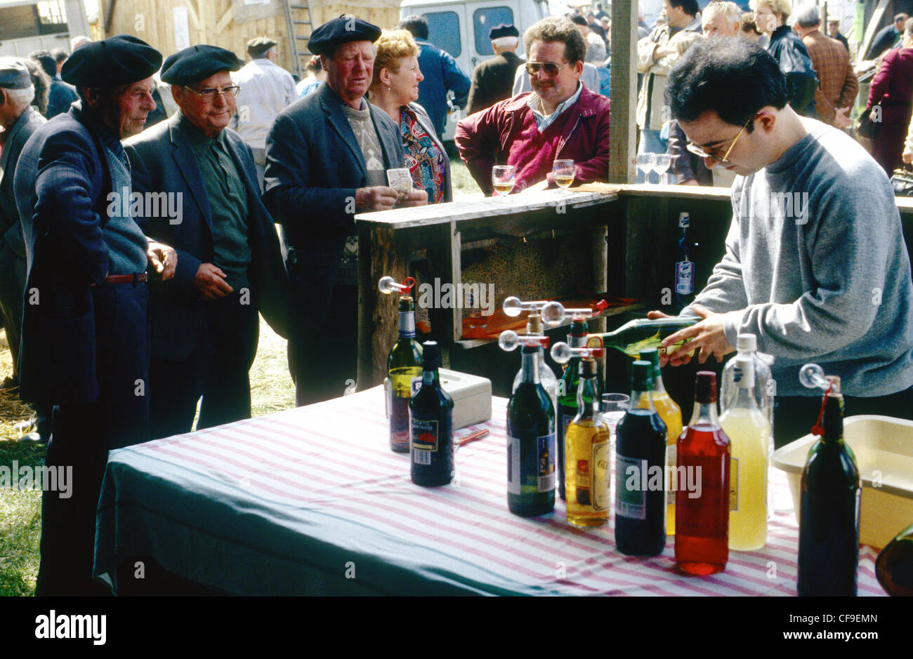 Un giovane uomo distribuisce bevande a una fiera di paese rurale in Francia (Lot) Foto Stock