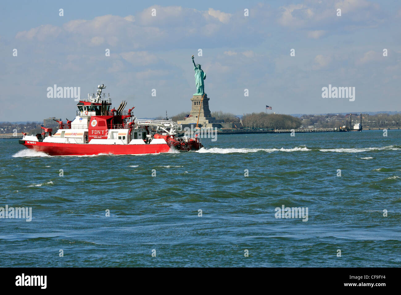 New York City Fire Department boatpassing la Statua della Libertà nel porto di New York al di fuori della Red Hook Brooklyn Foto Stock
