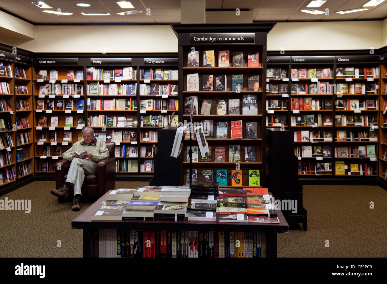 Un uomo seduto di lettura in una libreria Waterstones, Cambridge Regno Unito Foto Stock