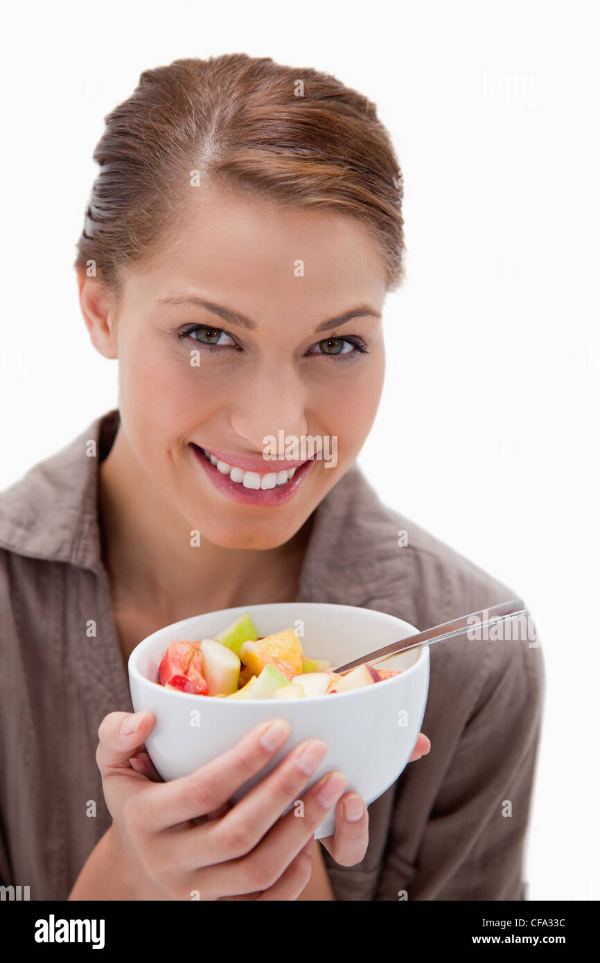 Donna sorridente con ciotola di insalata di frutta Foto Stock