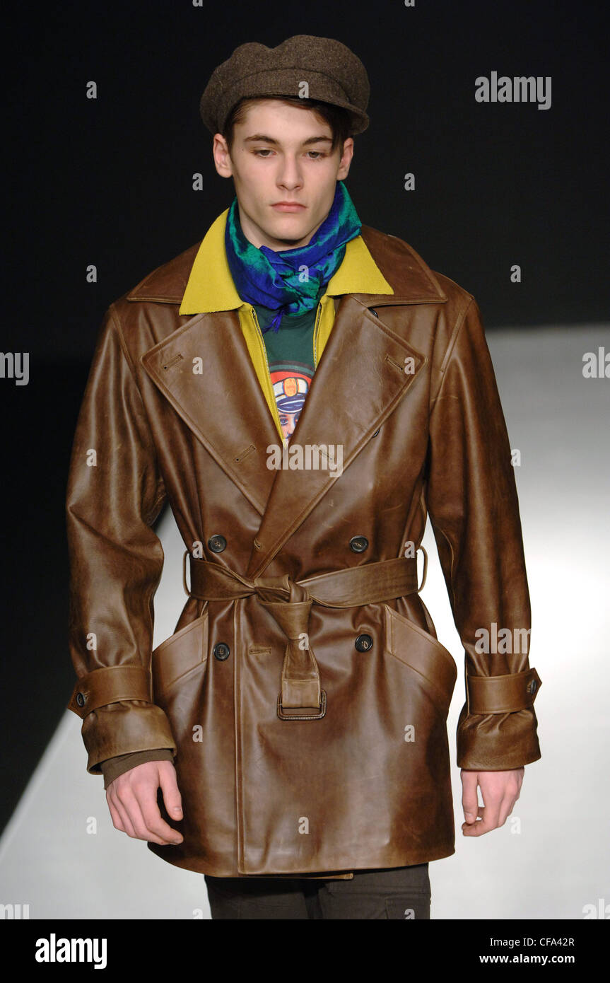 Agnes B pronto a indossare abbigliamento uomo Parigi A W Brunette modello indossa un doppio petto belted metà lunghezza della coscia giacca di pelle marrone Foto Stock