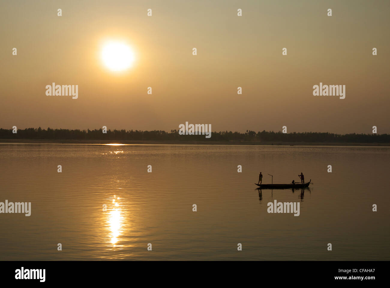 I pescatori le reti di impostazione come il sole tramonta oltre il Fiume Mekong, Kratie, Cambogia. Foto Stock