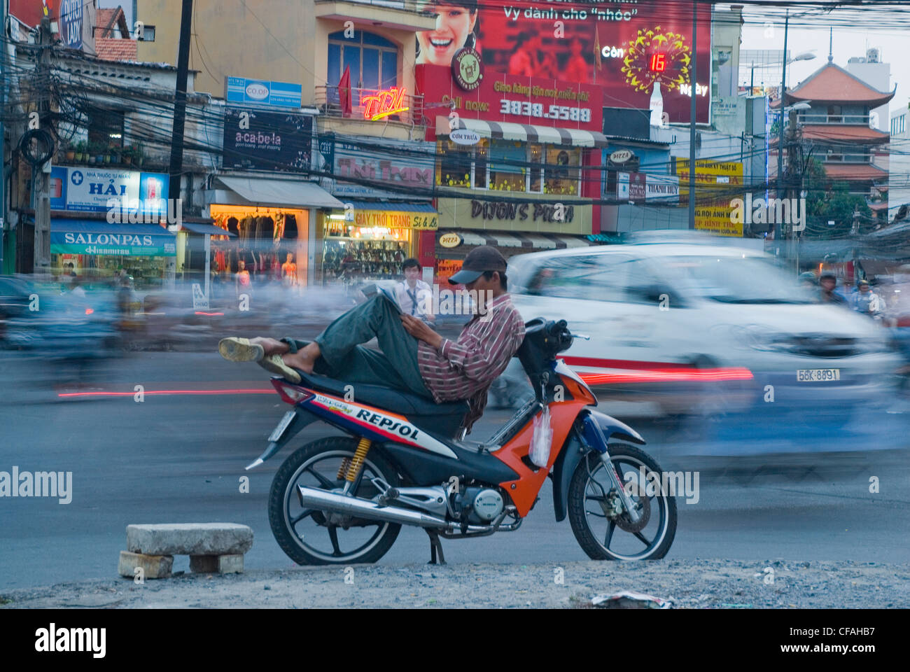 Prendendo una pausa di lettura su strade trafficate della città di Ho Chi Minh (Saigon), Vietnam. Foto Stock