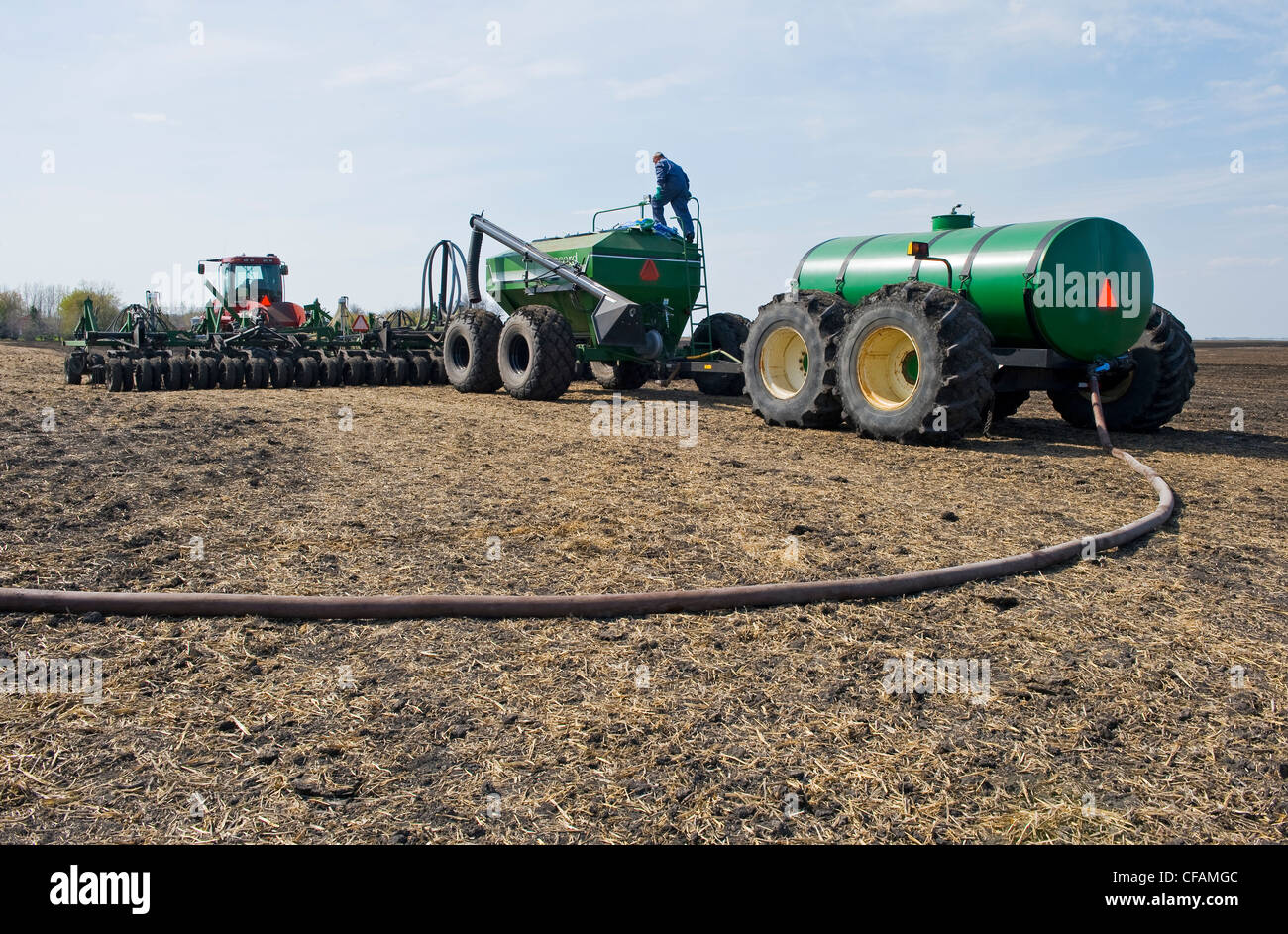 Un agricoltore carica un serbatoio della seminatrice con semi di canola e un altro serbatoio con fertilizzante liquido, nei pressi di Dugald, Manitoba, Canada Foto Stock