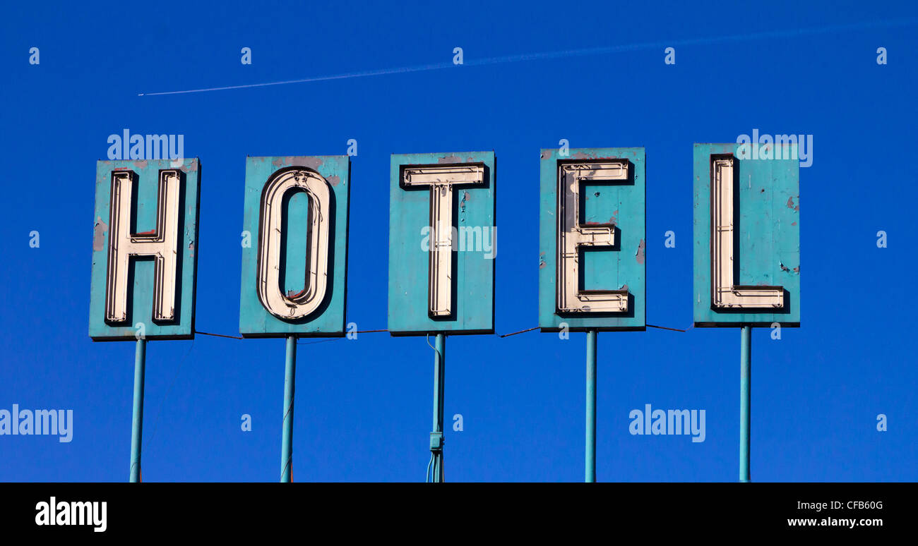 Grungy vecchio hotel isloated segno su un cielo blu lo sfondo con un aereo in volo la distanza Foto Stock