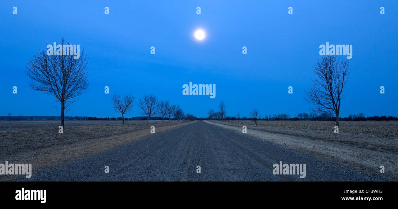 La luna sorge su questa strada di campagna nei pressi di Grand Bend, Ontario, Canada Foto Stock