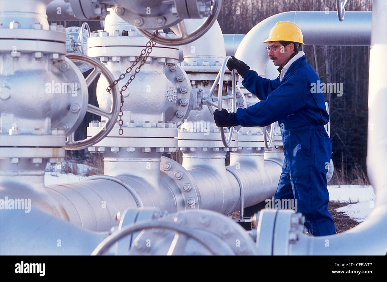 Industria petrolifera lavoratore ruotando la valvola sulla pipeline Foto Stock
