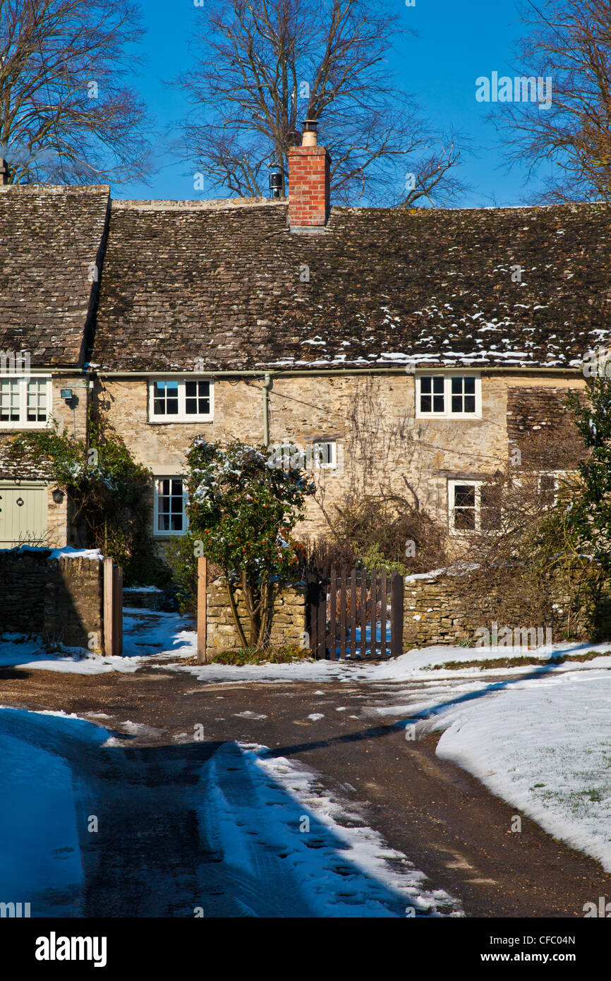 Una fila di pretty Cotswold cottage in pietra nella neve in Ampney San Pietro, Gloucestershire, England, Regno Unito Foto Stock
