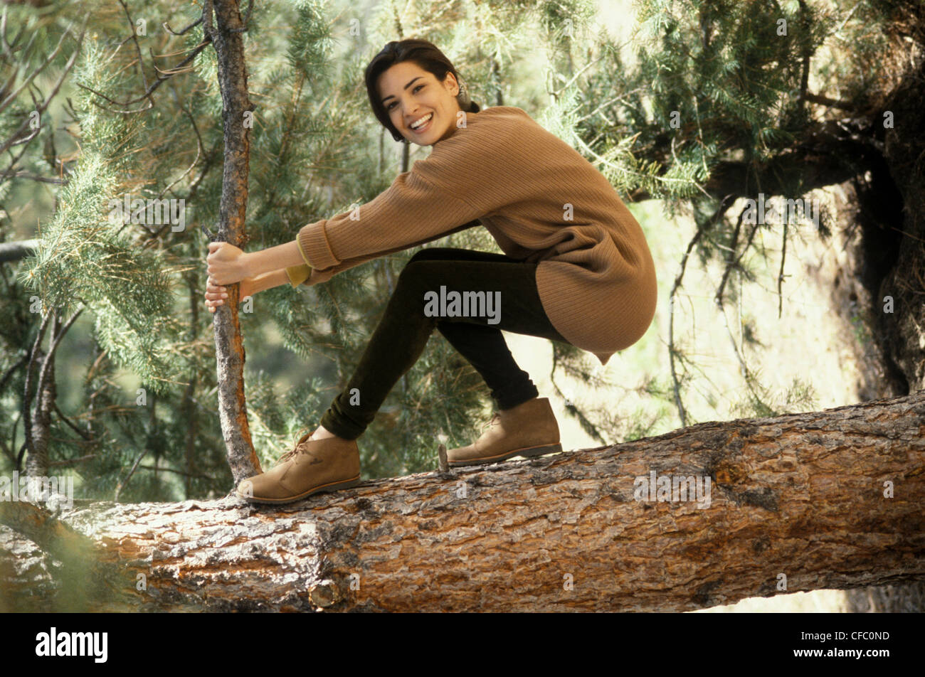 Donna che indossa un ponticello di beige, marrone leggings e tan Stivali di  arrampicata su un albero caduto tronco Foto stock - Alamy