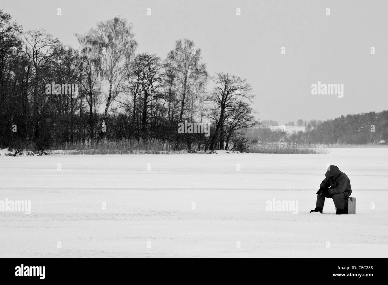 L'uomo la pesca nelle acque congelate del Lago Galvė, Trakai, Lituania (versione a colori disponibili in CFC28K) Foto Stock