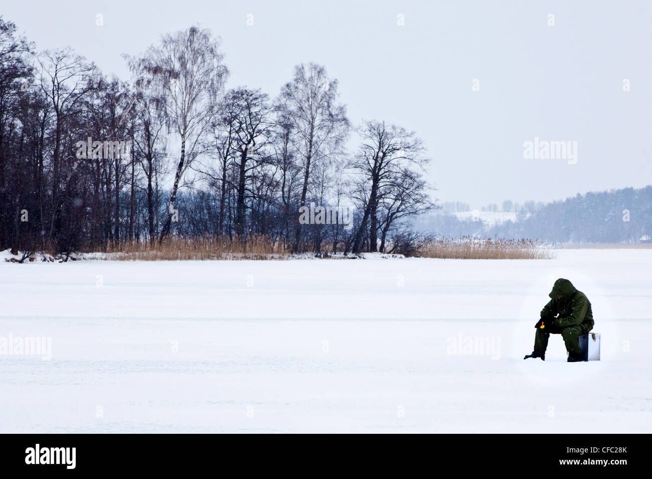 L'uomo la pesca nelle acque congelate del Lago Galvė, Trakai, Lituania (in bianco e nero disponibili presso il CFC288) Foto Stock