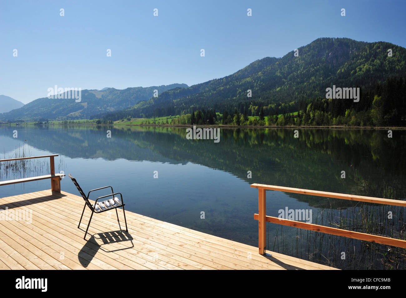 Ponton in legno con sedia per i bagnanti, il lago Weissensee, Carinzia, Austria, Europa Foto Stock