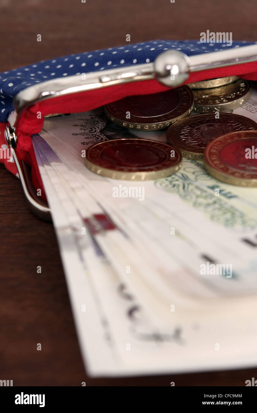 Sterling le banconote e le monete metalliche sporgenti di una signora della borsa Foto Stock