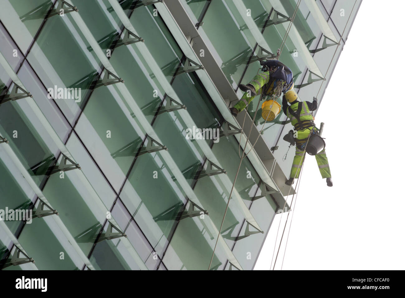 Detergenti per finestre a scalare marcia sono sospesi da funi al di fuori di un edificio alto. Foto Stock