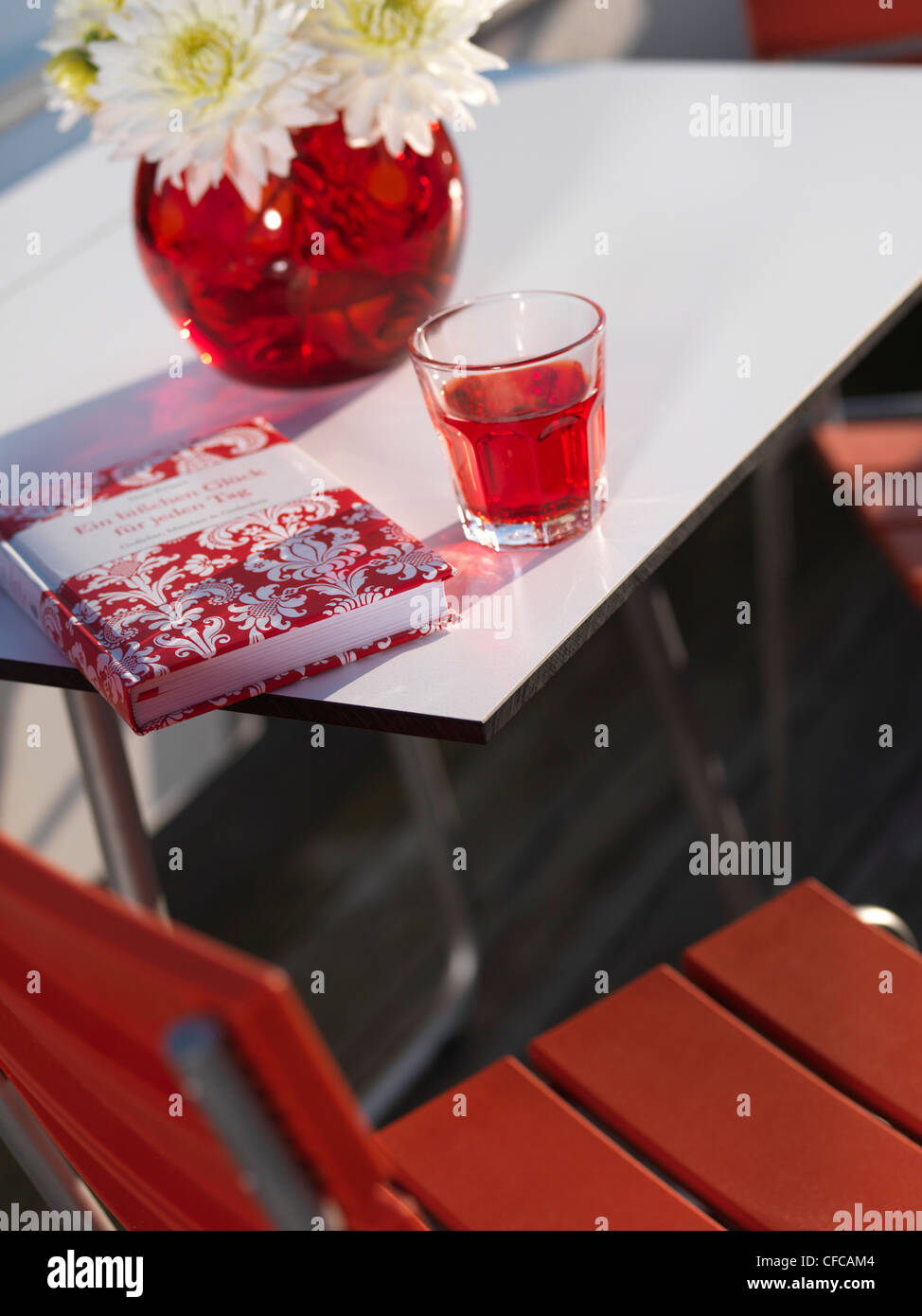 Decorate in modo moderno tavolo da giardino con libretto rosso e rosso bere, Kolbermoor, Baviera, Germania Foto Stock