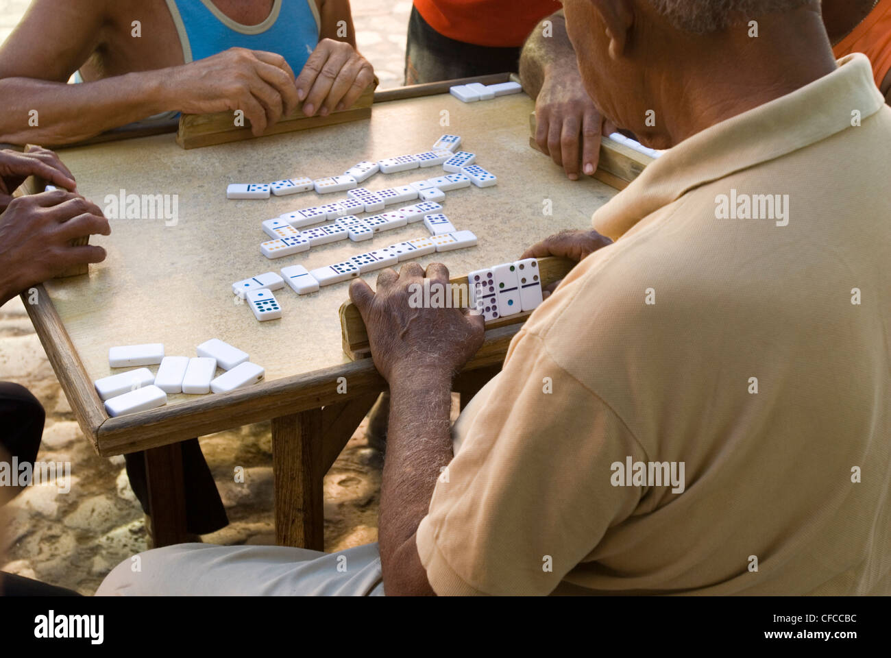 Un gruppo di anziani signori la riproduzione di un media gioco di domino per le strade di Trinidad, Cuba Foto Stock