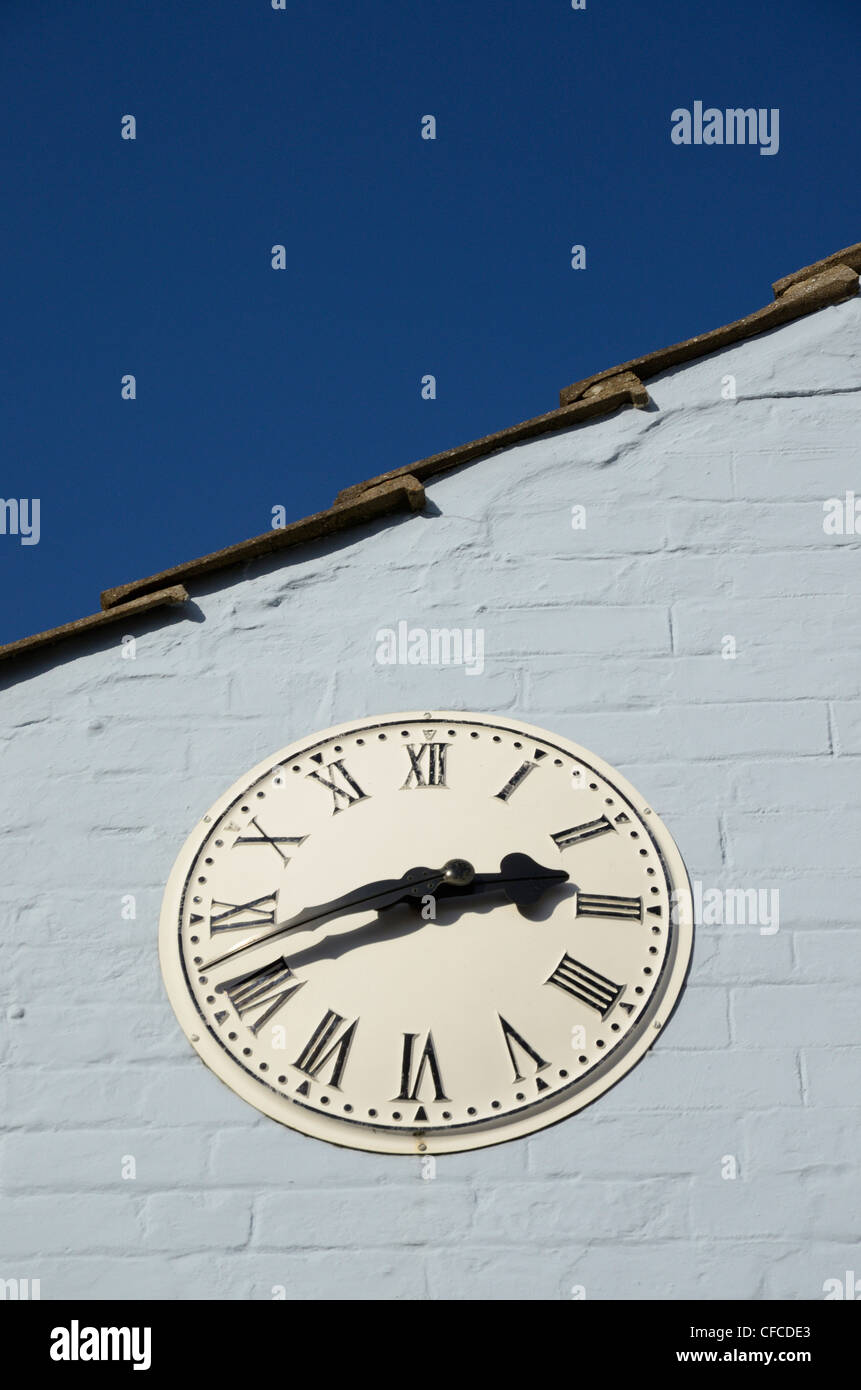 Al di fuori di un orologio con i numeri romani montato su parete blu, REGNO UNITO Foto Stock