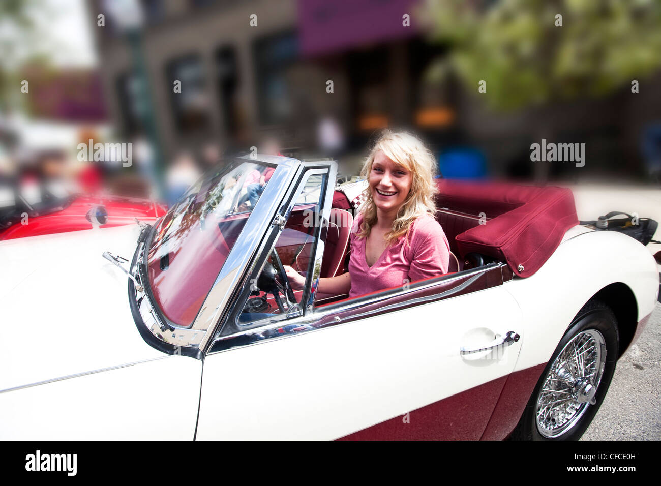 Una giovane e bella donna sorrisi mentre è seduto in un auto d'epoca in Idaho. Foto Stock