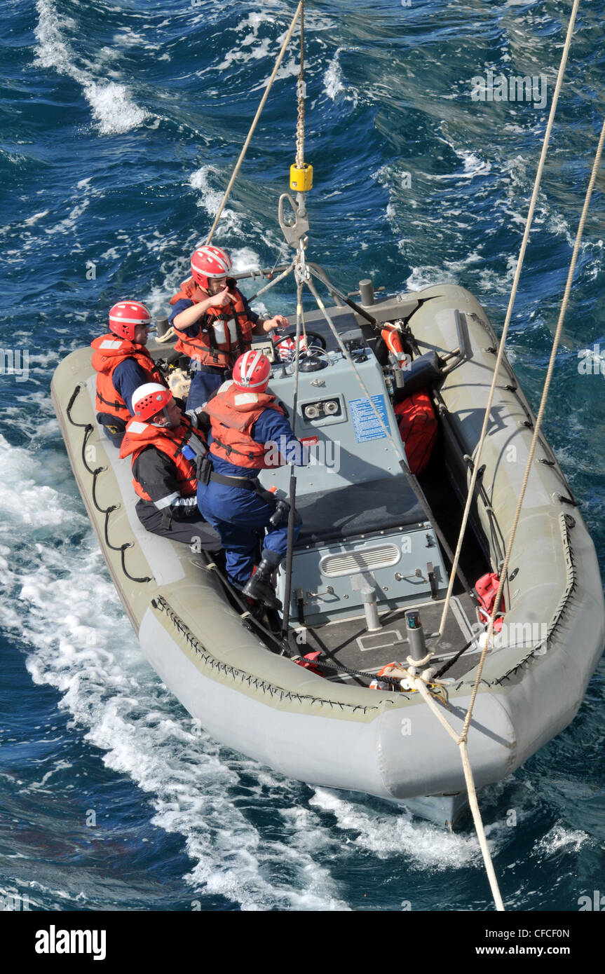 I marinai a bordo di una barca gonfiabile a scafo rigido vengono abbassati in mare dalla nave d'assalto anfibia USS Kearsarge durante un'esercitazione di uomo a bordo. Kearsarge è in corso, completando la formazione di base del Gruppo di formazione a distanza 1.3. Foto Stock