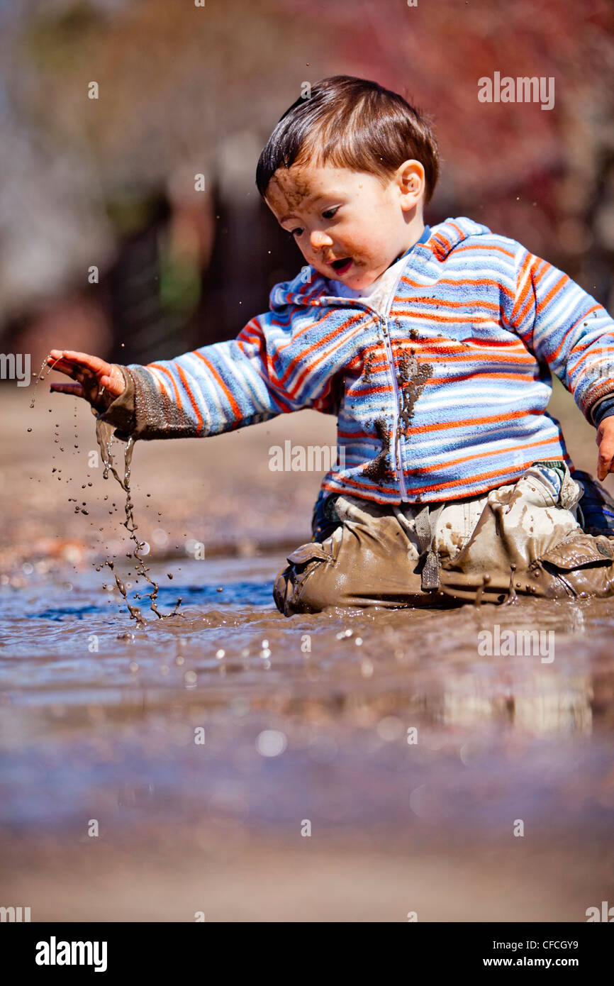Un bimbo di 2 anni, gioca in una pozza di fango. Foto Stock