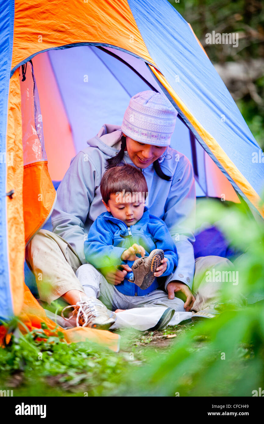 Una madre e figlio siedono in blu e arancione tenda e mettere le loro scarpe, sulla loro campeggio che è a circa 10,120 piedi Foto Stock
