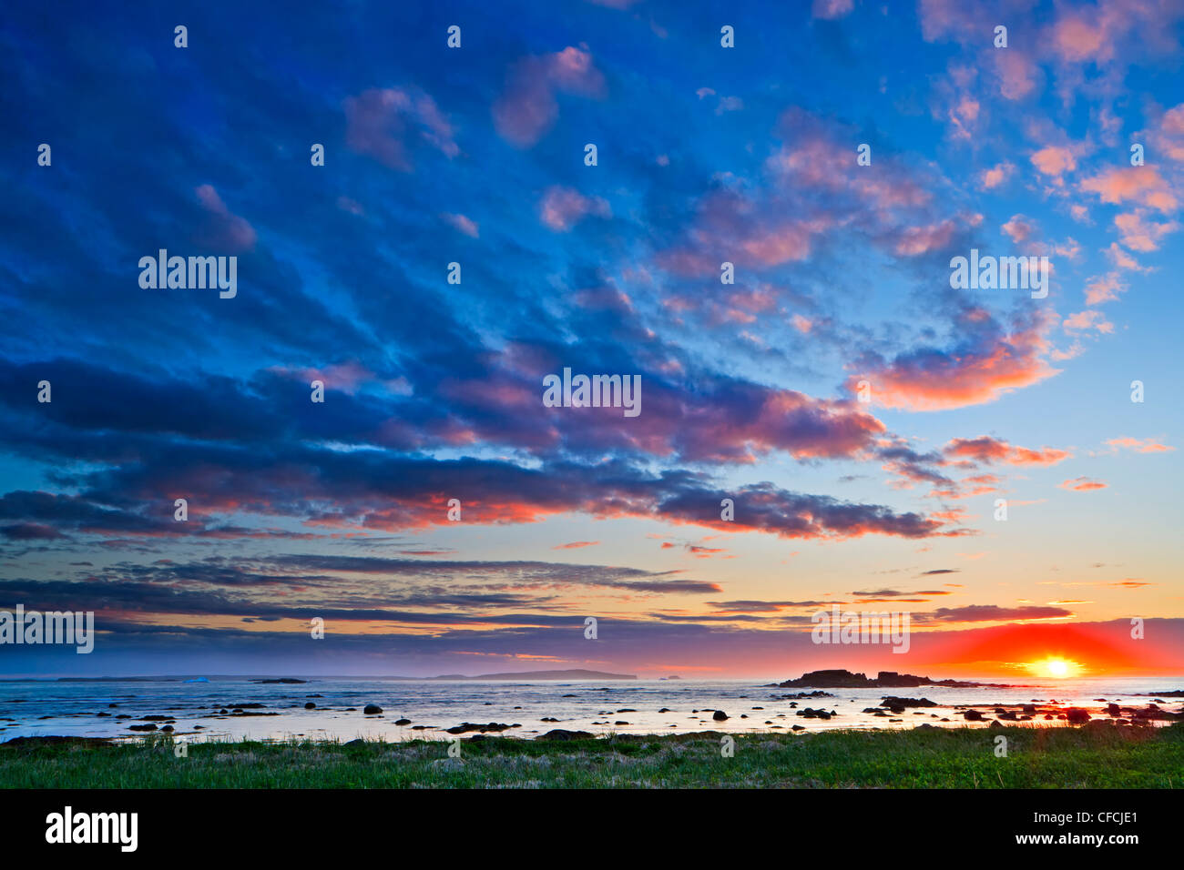 Tramonto con belle nuvole sopra una frastagliata isola rocciosa off shore dalla città di L'Anse aux Meadows, nel nord della penisola, Newf Foto Stock
