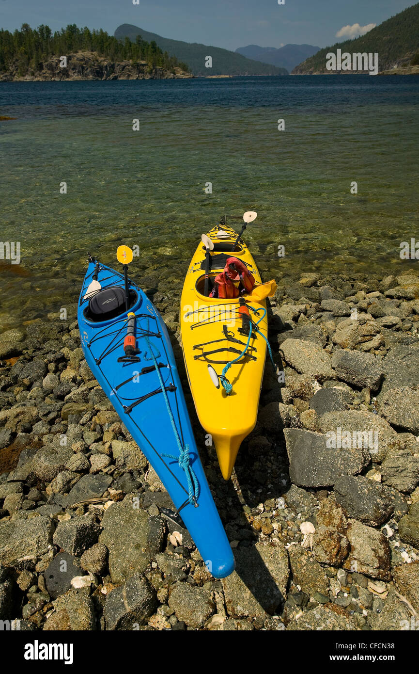 Colorato kayak tirato verso l'alto lungo le rive della desolazione attendono il suono dei loro proprietari. Desolazione Suono, British Columbia, Canada. Foto Stock