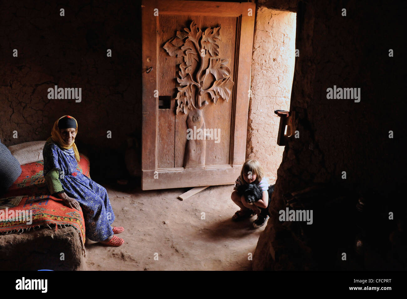 Vecchia donna Berbera e giovane ragazza europea in una tradizionale casa Berber con ornato porta, Kasbah Ait Benhaddou, Ait Benhaddou, ATL Foto Stock