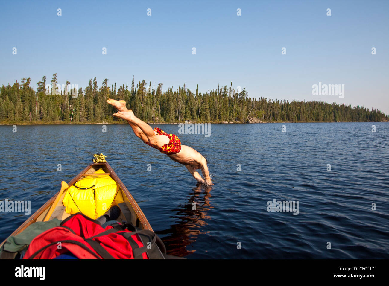 Un uomo il raffreddamento e le immersioni in un lago in una giornata calda mentre canoa e campeggio in Wabakimi Parco Provinciale, Ontario, Canada Foto Stock