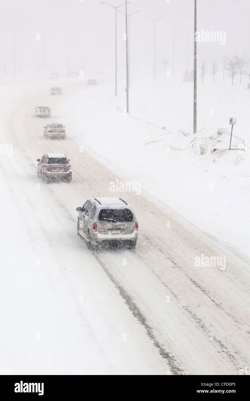 Il traffico su una coperta di neve su strada, durante una tempesta di neve in inverno. Winnipeg, Manitoba, Canada. Foto Stock