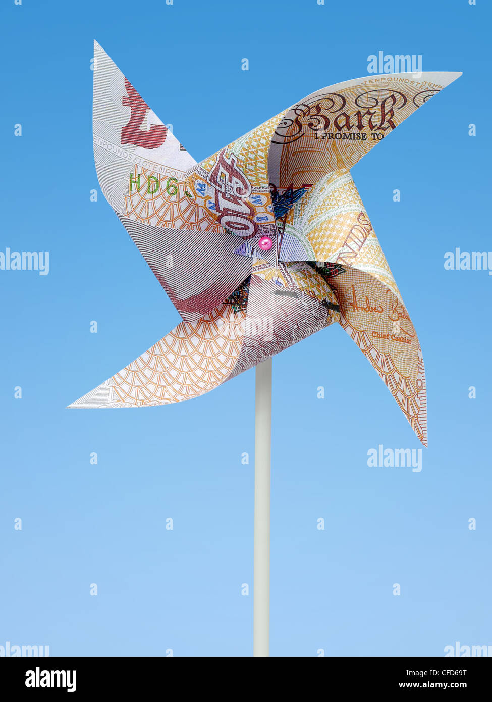 Sterlina britannica banconota tagliato in toy windmill shot su sfondo blu Foto Stock