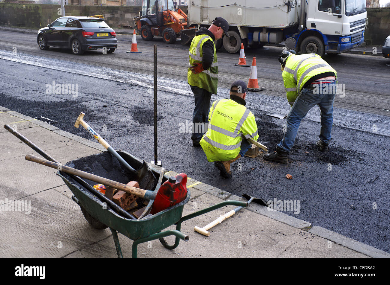 Tre operai la riparazione della superficie stradale danno con buche ed erosione di acqua, Glasgow, Scotland, Regno Unito, Gran Bretagna Foto Stock